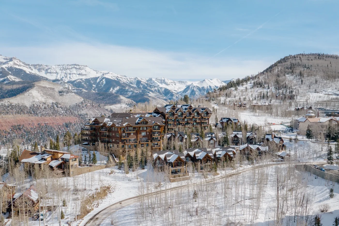 A snowy mountain resort village with clustered buildings beneath a range of snow-covered peaks.