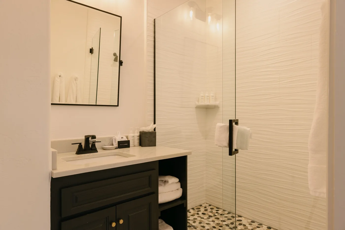 A bathroom vanity with a mirror beside a glass shower.