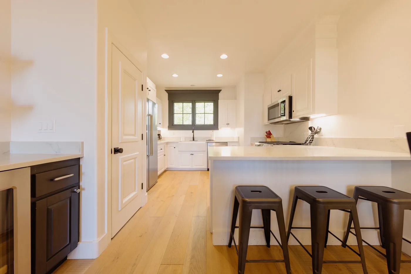 A bright kitchen with a central counter and bar seating.