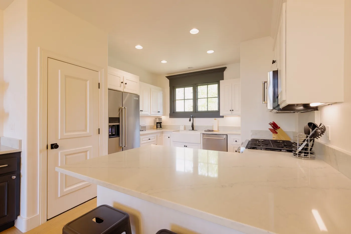 A bright kitchen with white cabinets, a large island, and a window over the sink.