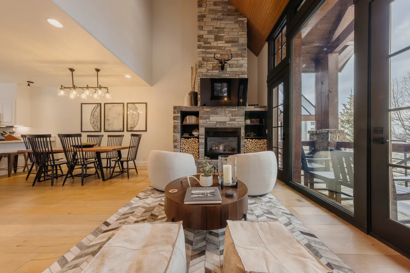An open living and dining area with seating around a fireplace and large windows.