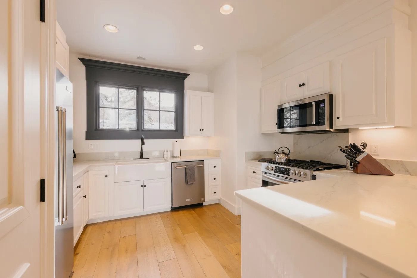 A bright kitchen with white cabinetry, a large island, and a window above the sink.