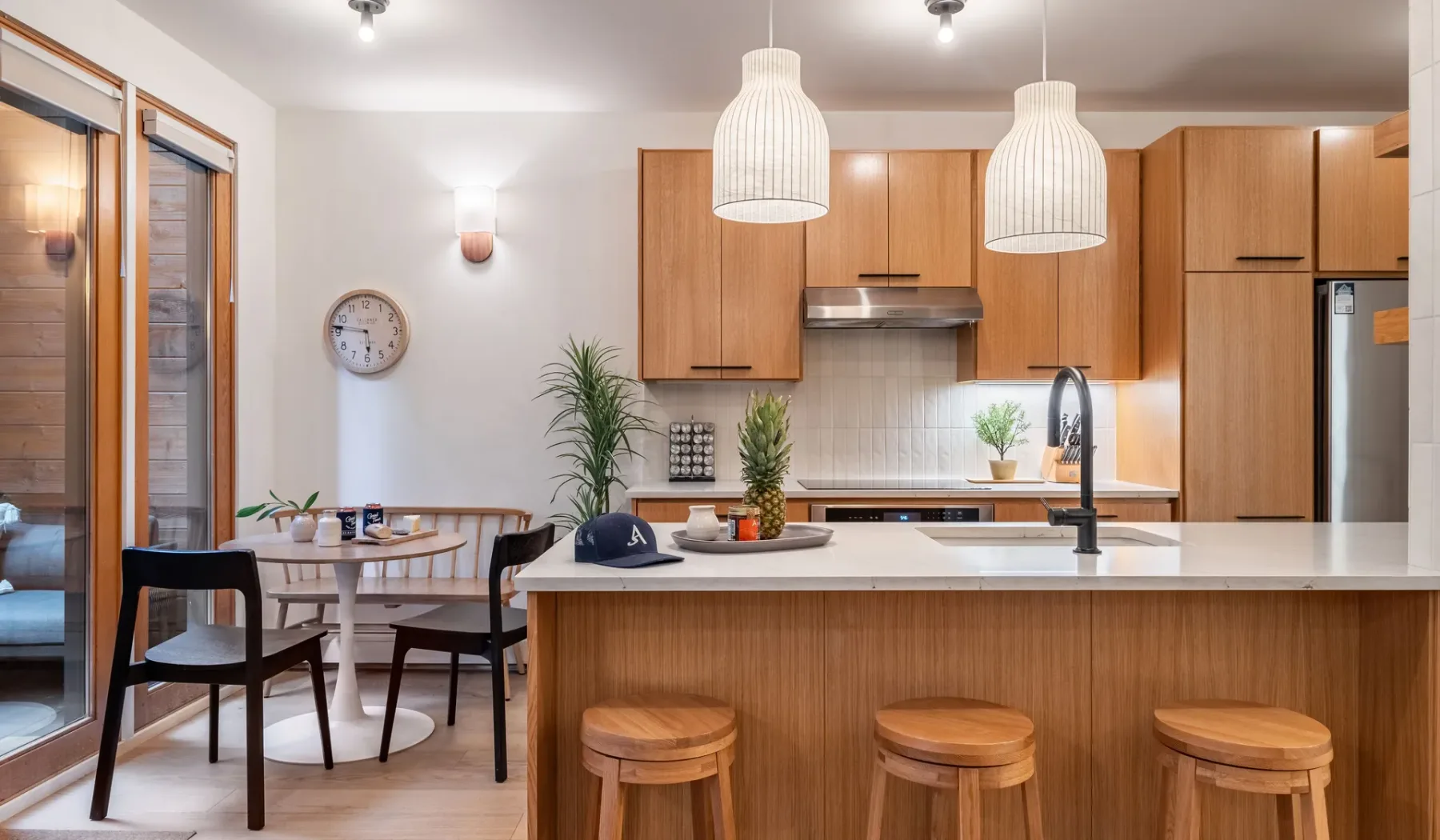 Una cocina luminosa con una isla de frentes de madera y una pequeña zona de comedor.