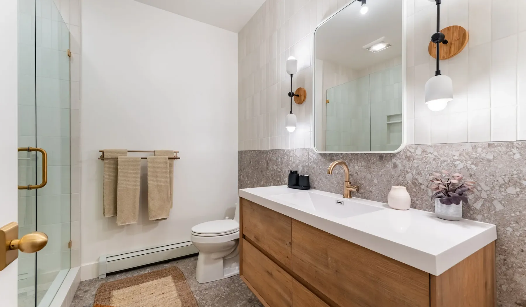 Baño con un tocador largo, espejo y ducha de vidrio.