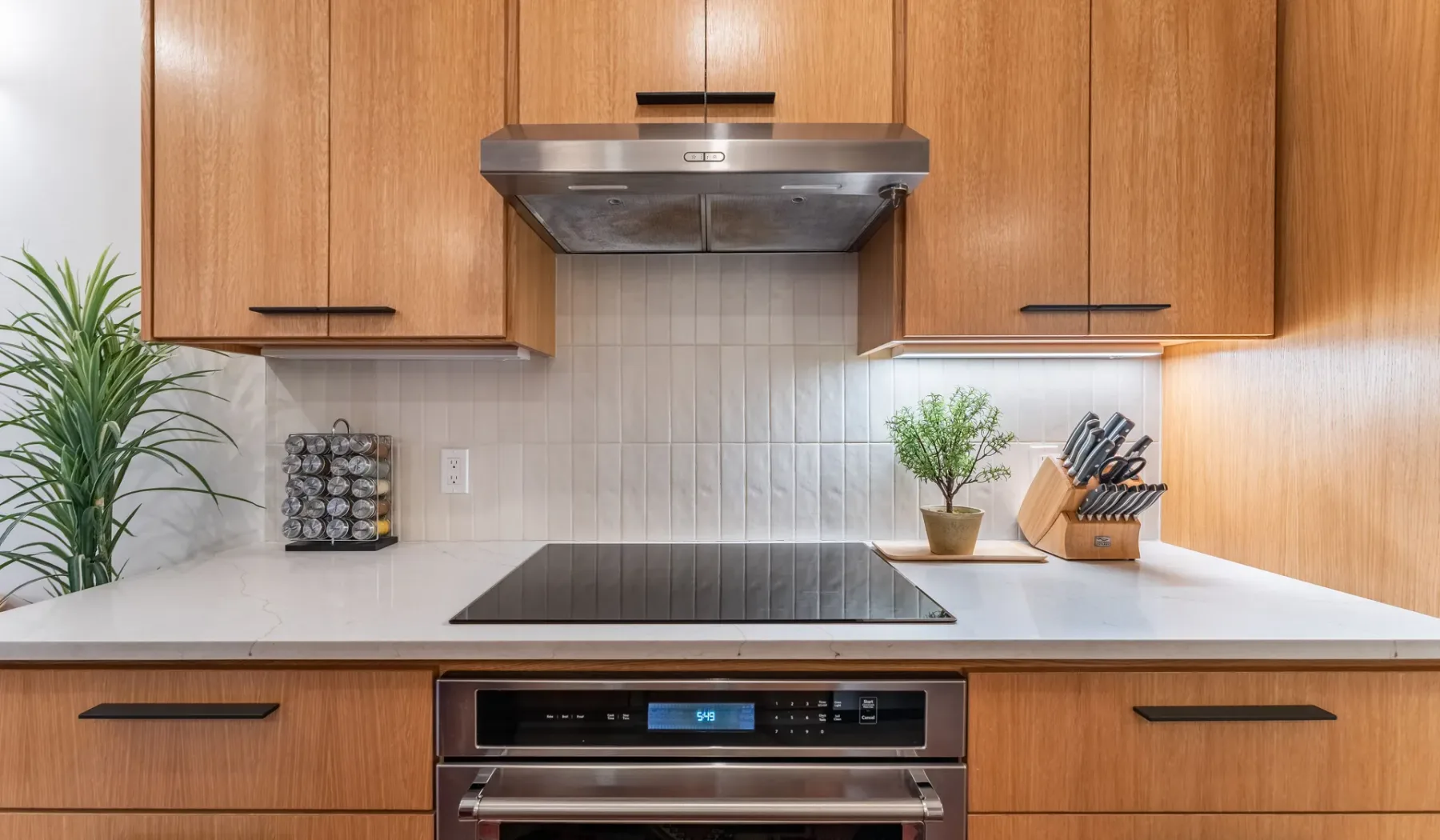 Una cocina moderna con gabinetes de madera, una placa de cocina y una campana extractora de acero inoxidable.