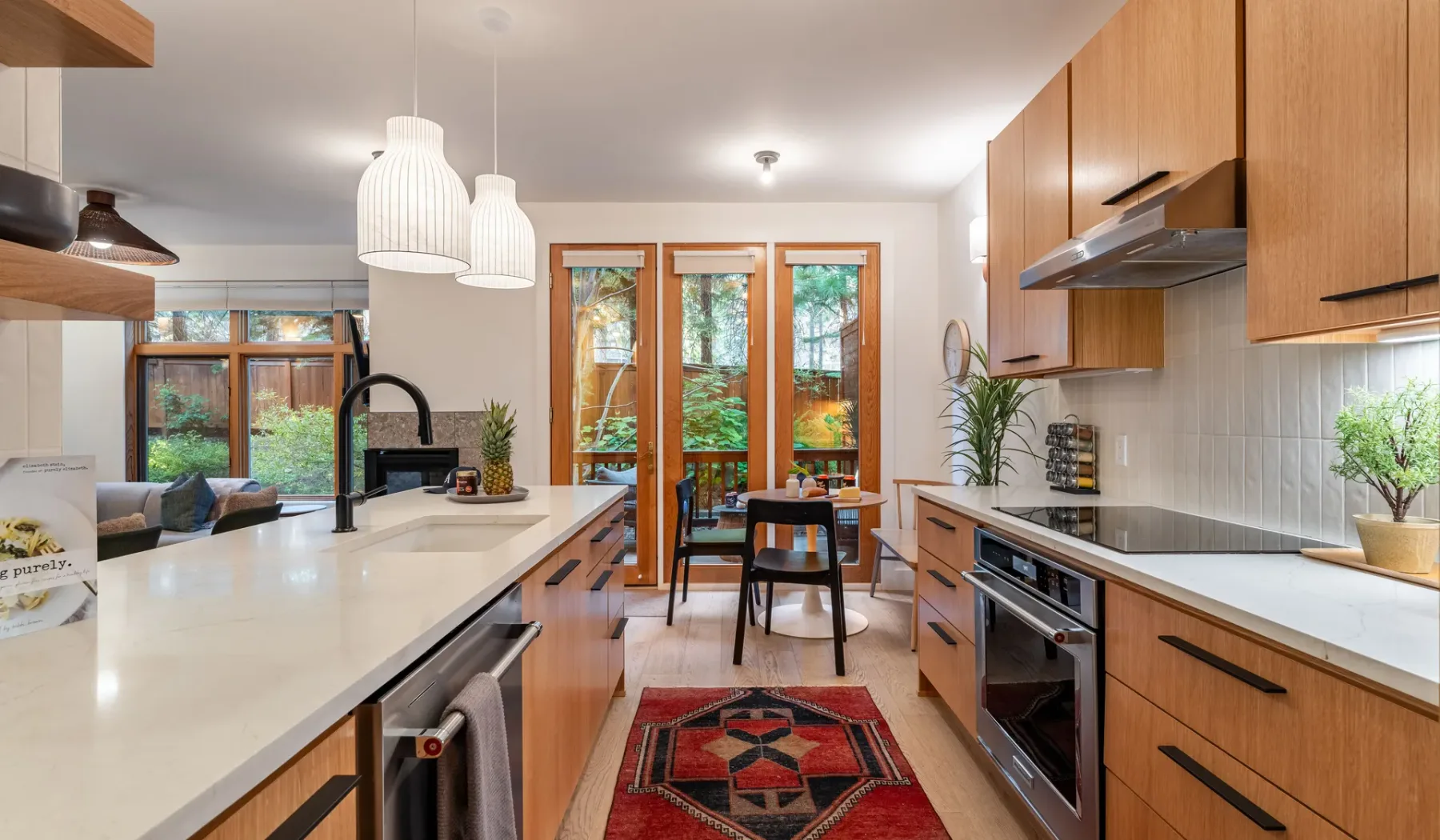 Una cocina luminosa con una isla central, armarios de madera y ventanas con vistas a la vegetación.