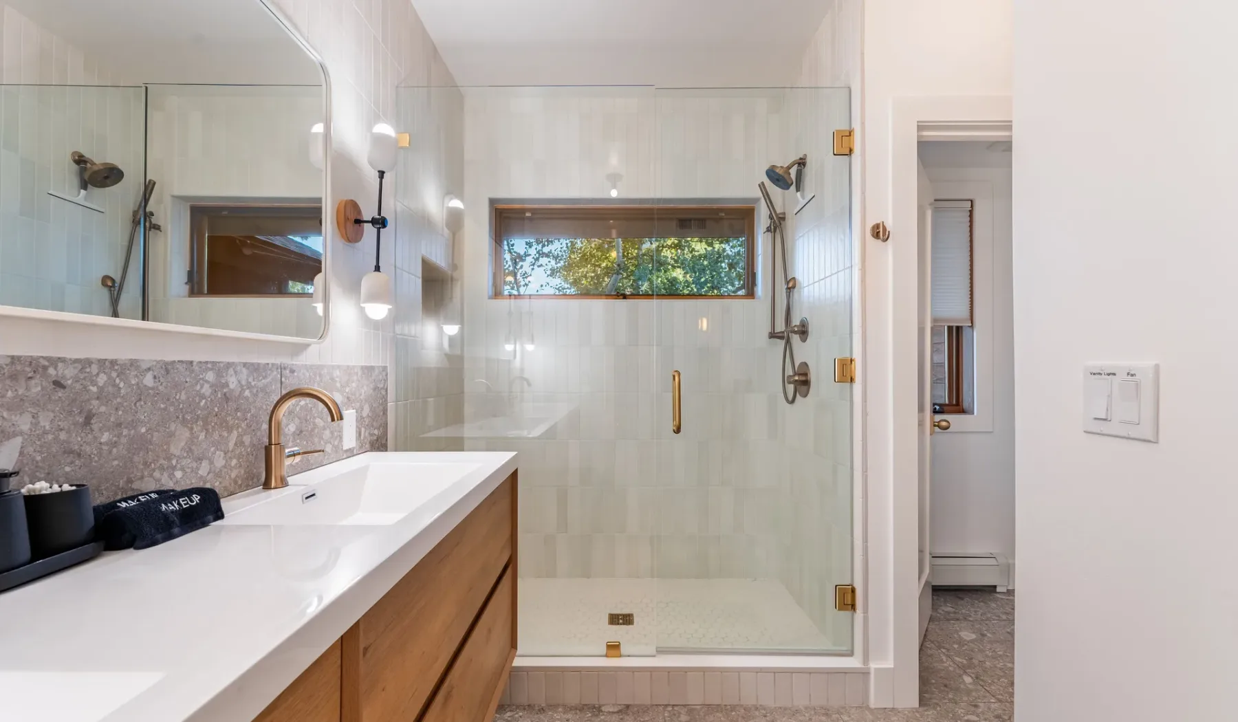 Un baño luminoso con un tocador largo y una ducha con mampara de vidrio.