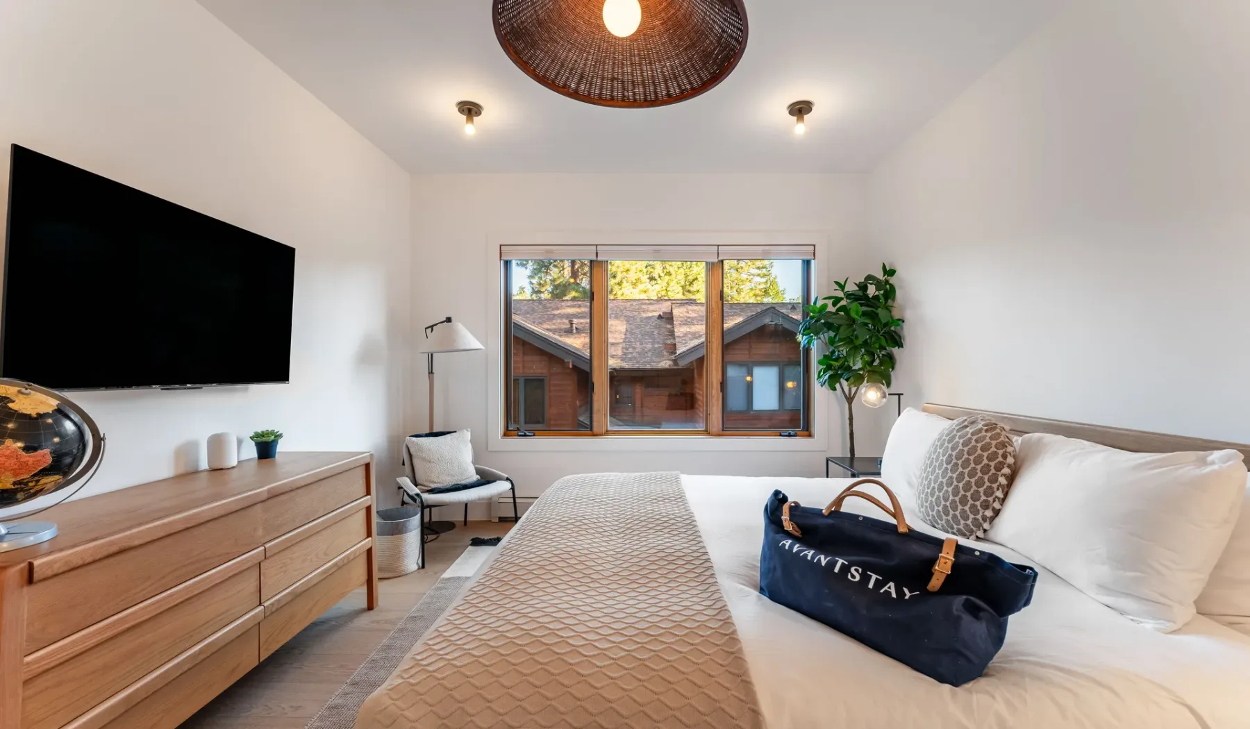 Un dormitorio luminoso con una cama, un televisor de pared y una ventana.