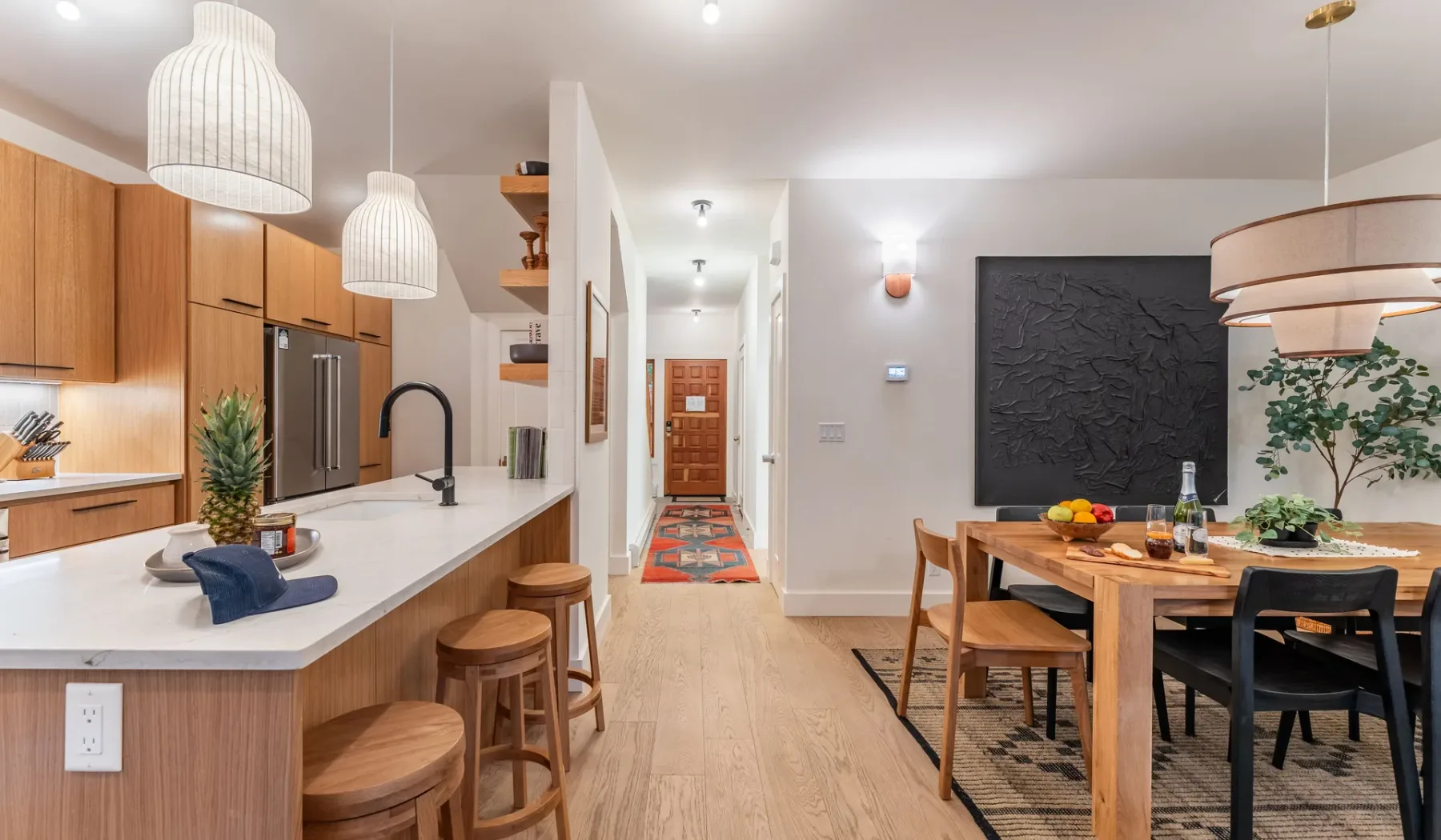 Una cocina abierta y zona de comedor con una barra larga y una mesa de madera.