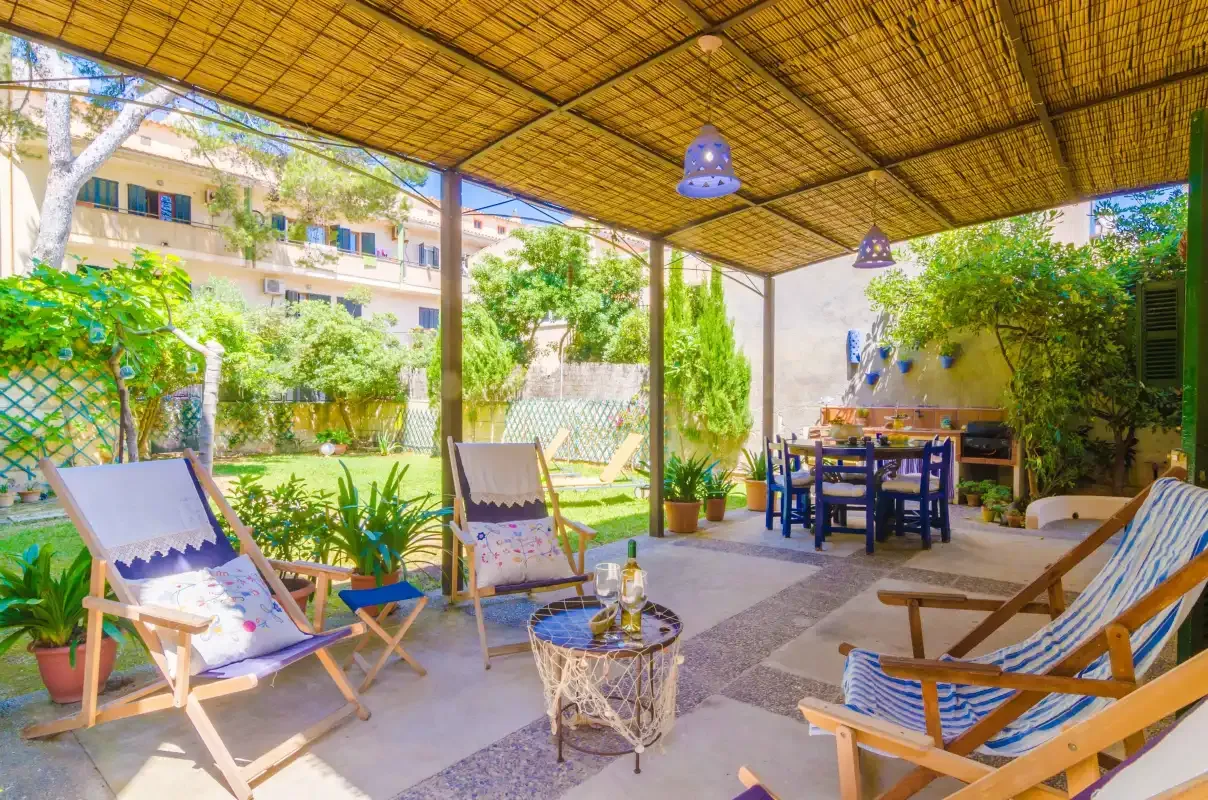 Un patio exterior sombreado con asientos y una mesa de comedor bajo un toldo tejido.