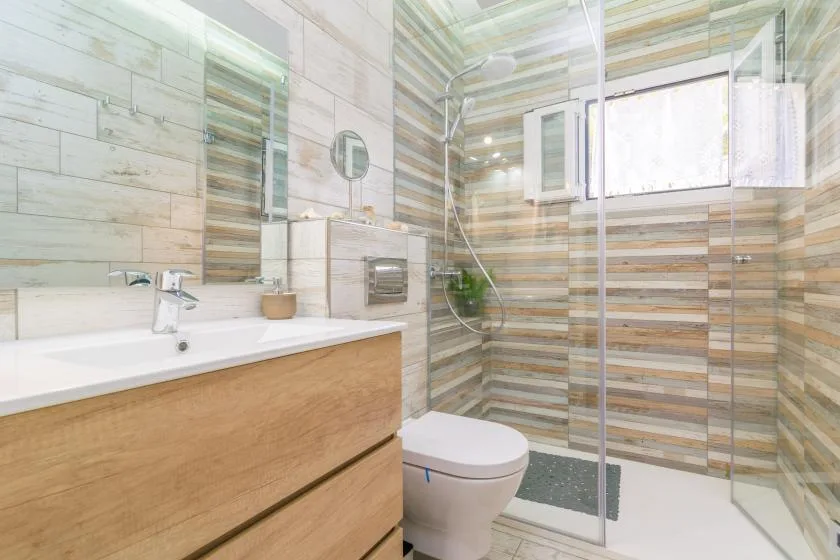 Un baño moderno con lavabo, inodoro y ducha con mampara de vidrio.