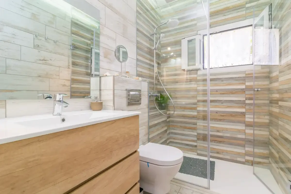 Un baño con un mueble de lavabo alargado y una ducha acristalada.