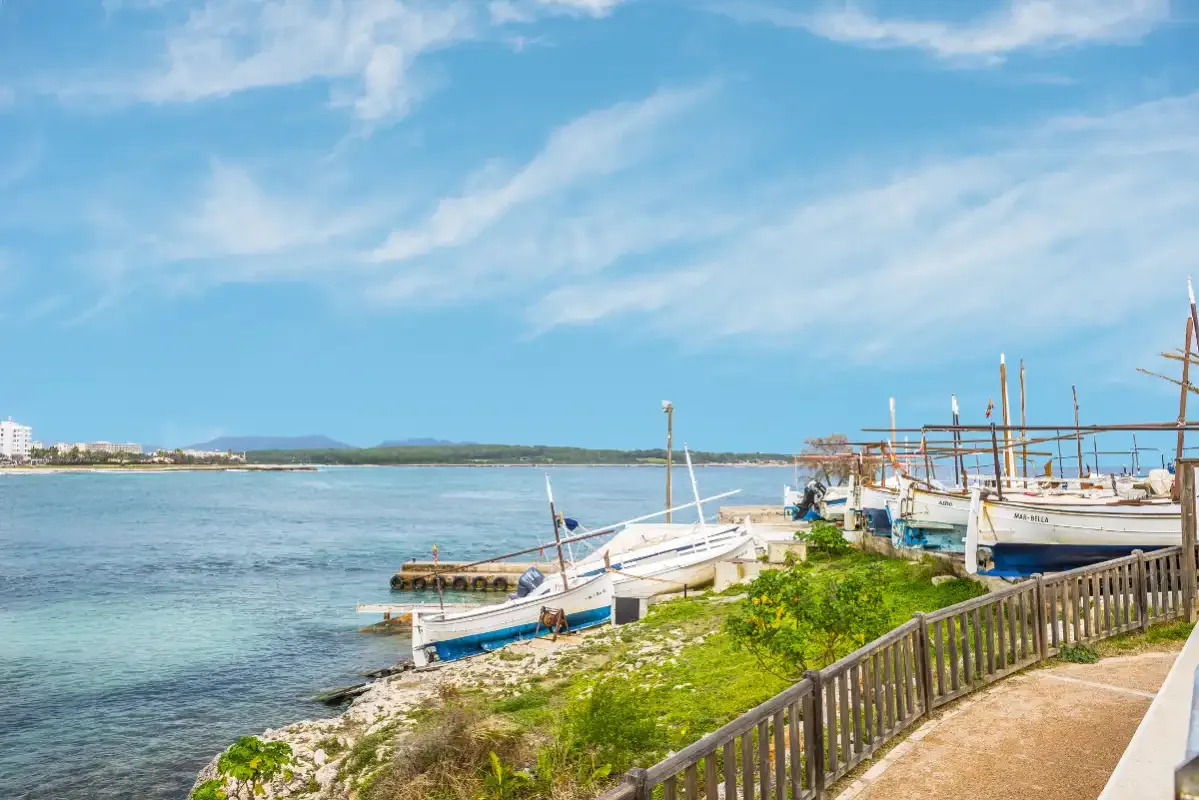 Un puerto costero con barcos amarrados junto a una barandilla de madera.