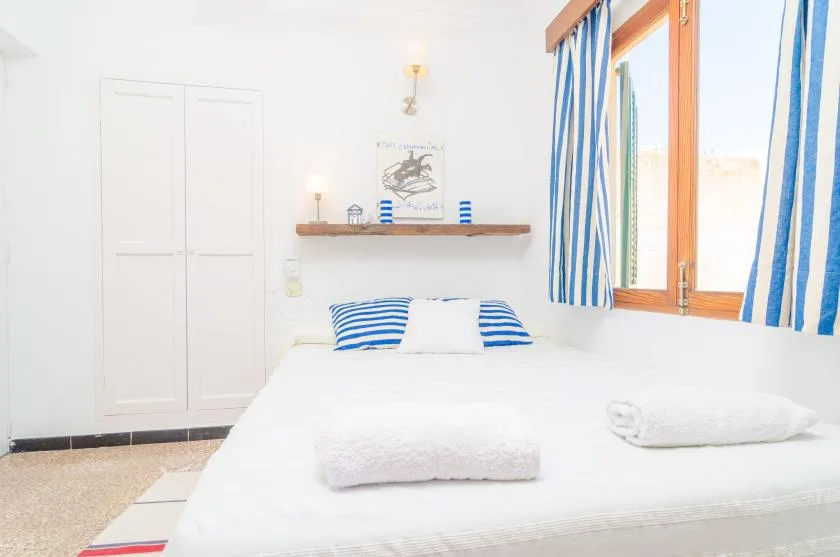 Un dormitorio luminoso con cortinas de rayas azules y una cama tendida.