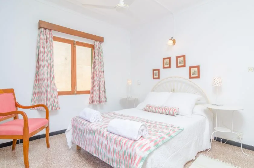 Un dormitorio luminoso con una cama doble, ropa de cama estampada y una ventana con cortinas.