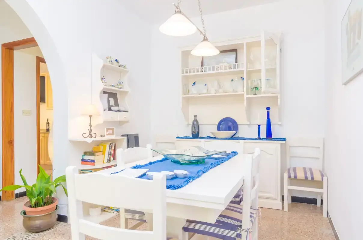 Un comedor luminoso con asientos blancos y detalles azules.