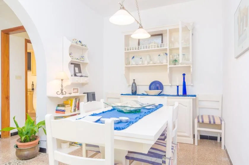 Un comedor luminoso con una mesa blanca y detalles azules.