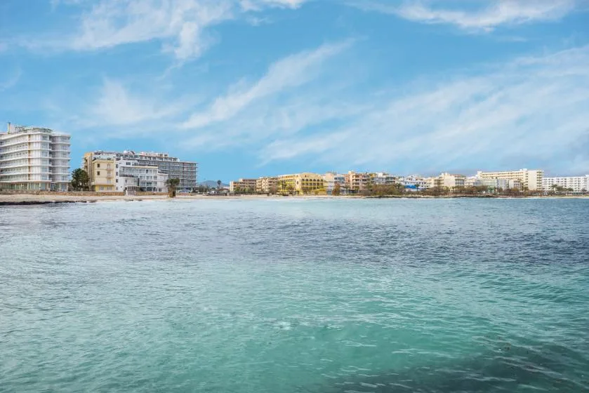 Un paseo costero con edificios junto a la orilla y aguas azules tranquilas.