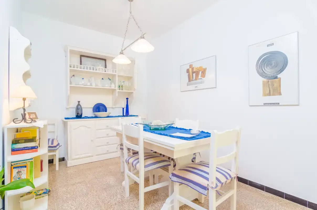Un comedor luminoso con una mesa, sillas y estanterías empotradas.
