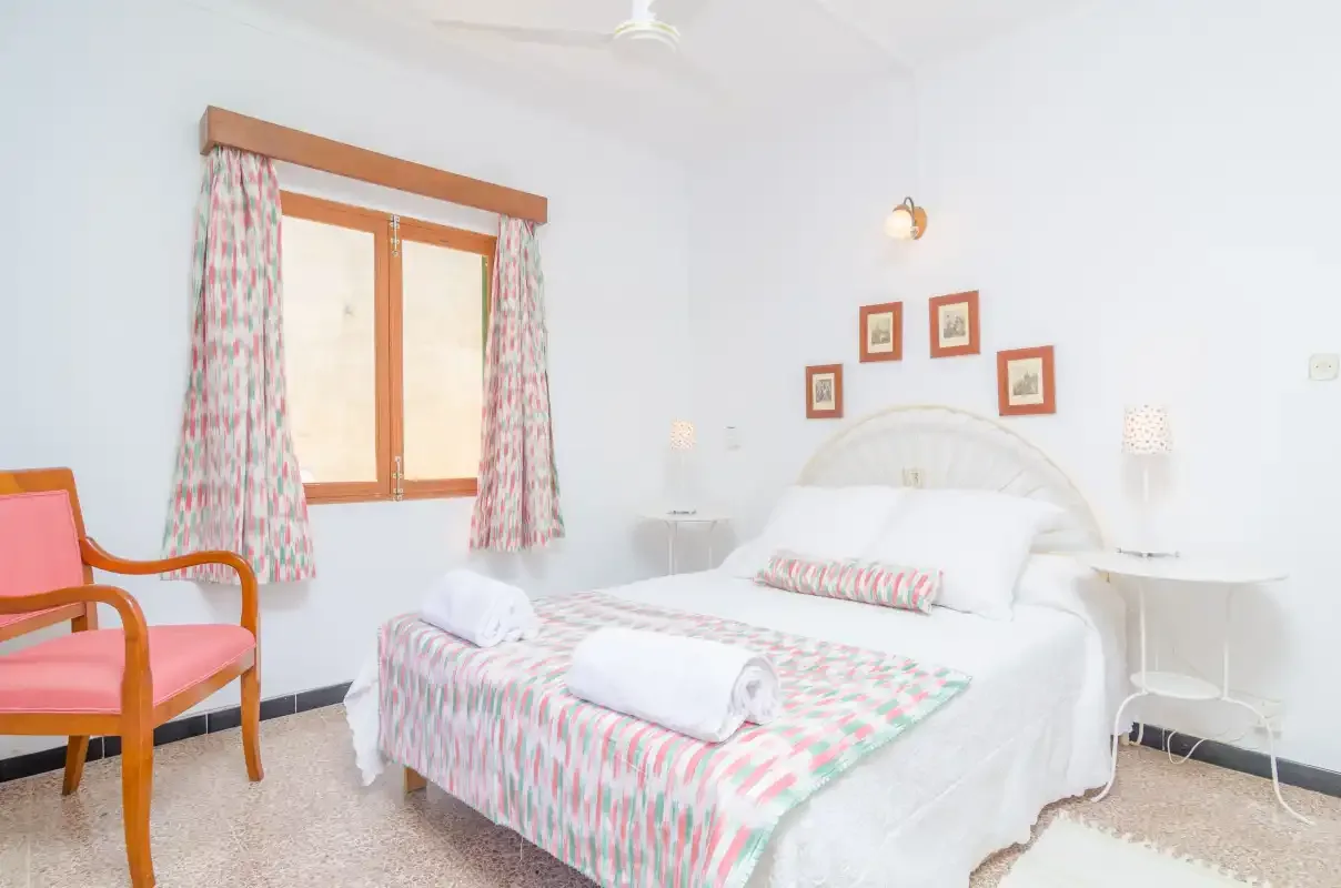 Un dormitorio con una cama vestida con ropa de cama estampada y una ventana con cortinas.