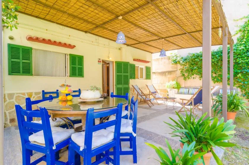 Comedor exterior cubierto con asientos azules y una mesa.