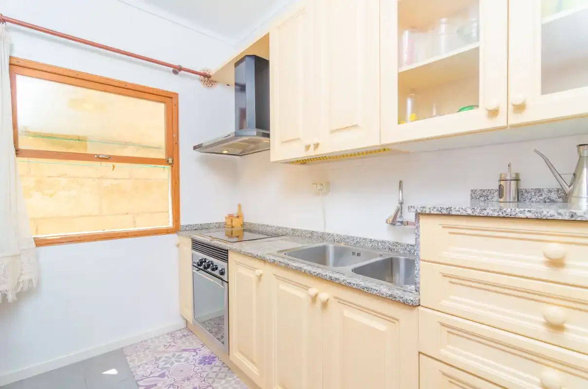 Una cocina luminosa con armarios claros, una encimera y un fregadero.