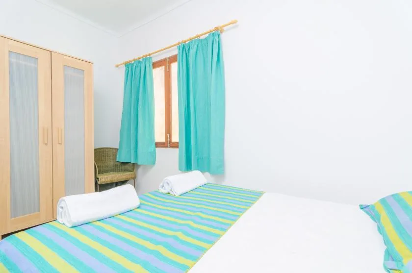 Un dormitorio con una colcha a rayas y cortinas turquesas.