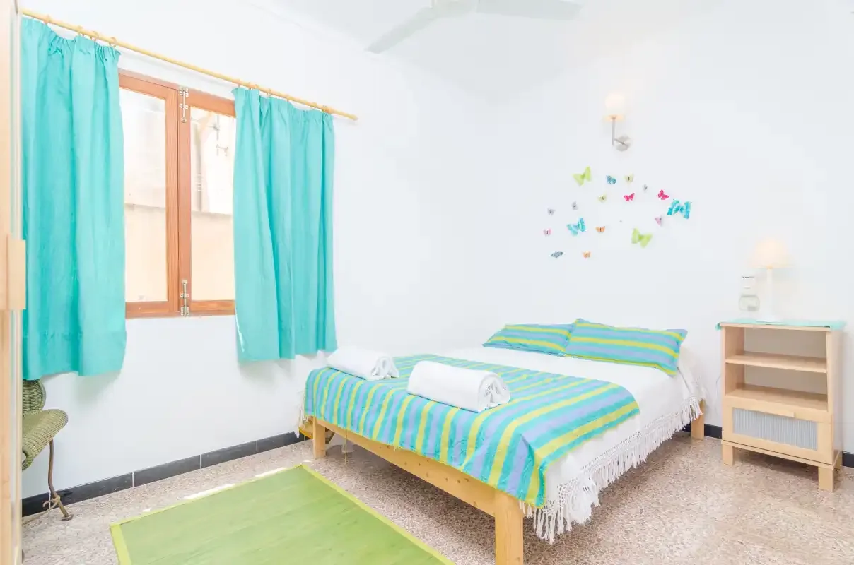 Un dormitorio luminoso con cortinas turquesas y una cama colorida.