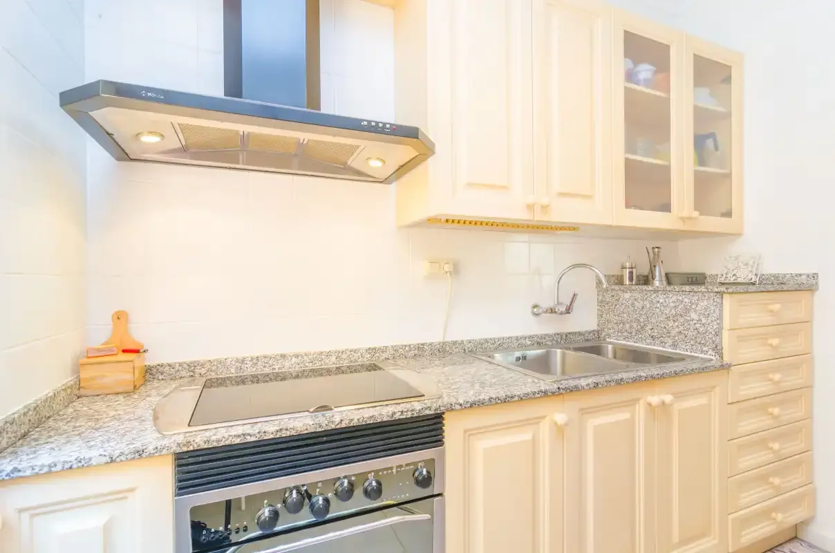 Una cocina luminosa con encimera, fregadero y horno.