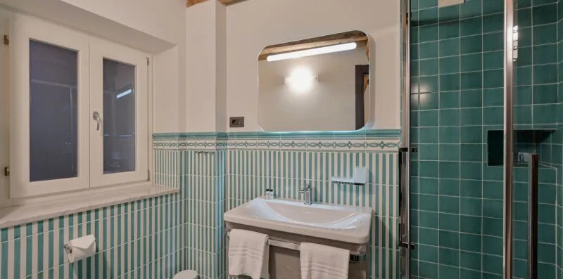 Un baño con azulejos, lavabo, espejo y ducha de vidrio.