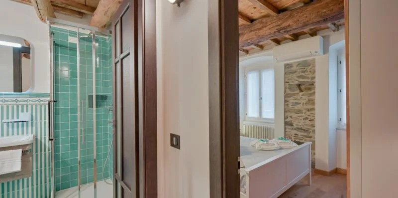 Un baño con una ducha alicatada junto a un lavabo y una pared de piedra.