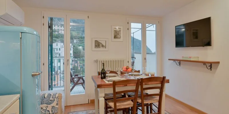 Comedor con mesa y sillas de madera junto a ventanas altas.