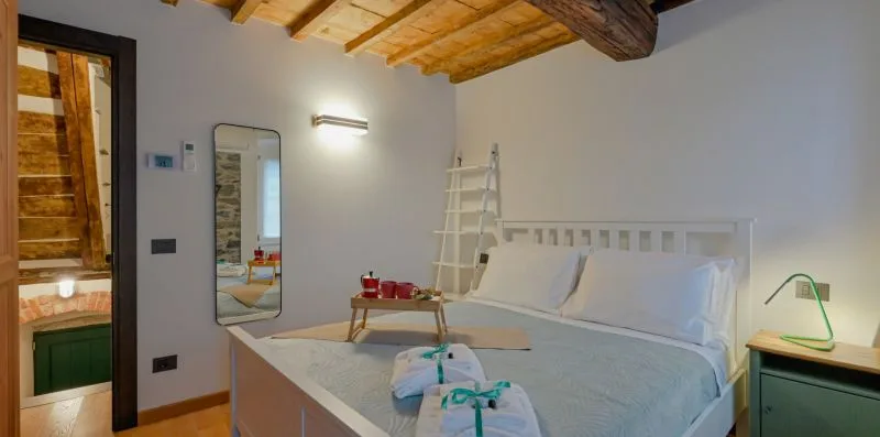 Un dormitorio con una cama grande, una mesita de noche y vigas de madera expuestas en el techo.