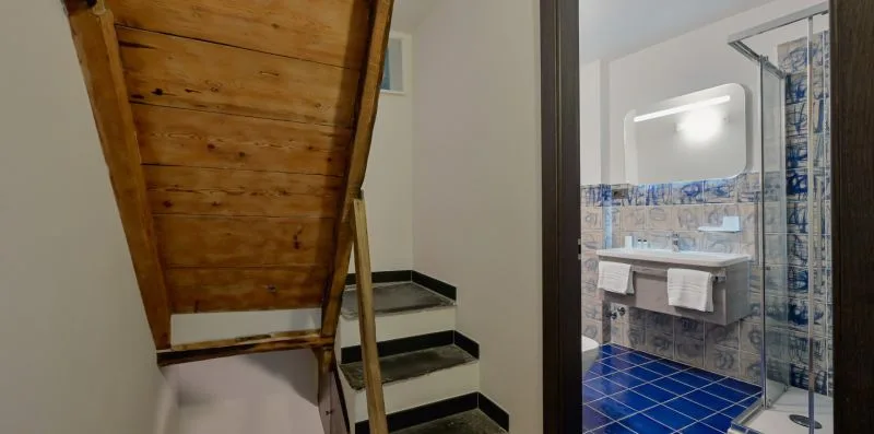 Una escalera junto a un baño con suelo de baldosas azules y un lavabo.