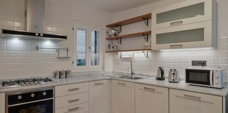 Una cocina luminosa con gabinetes blancos, encimera y horno empotrado.