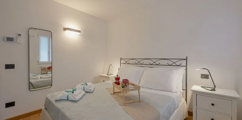 Un dormitorio luminoso con una cama y una mesita al lado.
