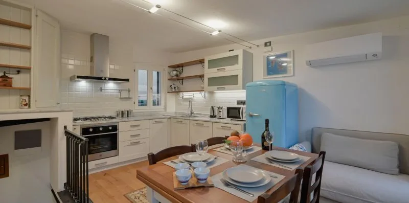 Una cocina y comedor con un refrigerador azul y una mesa puesta.