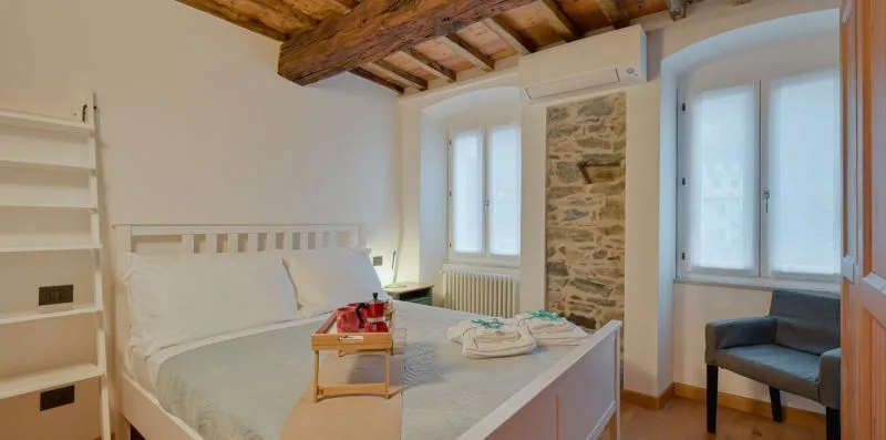 Un dormitorio con cama, vigas de madera expuestas y una pared de piedra.