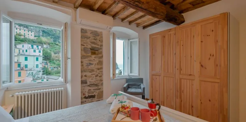 Una habitación luminosa con grandes ventanas, una pared de piedra y muebles de madera.