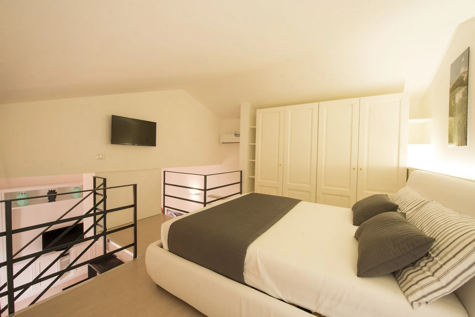 A bedroom with a bed, wardrobes, and a railing beside the stair opening.