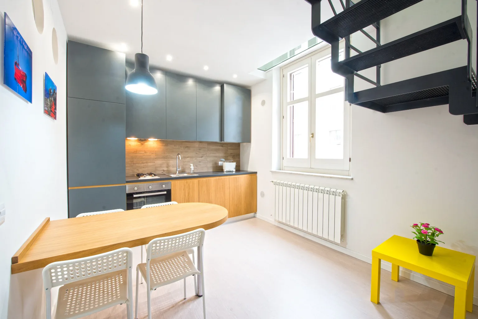 A bright kitchen and dining area with gray cabinets and a wooden table.