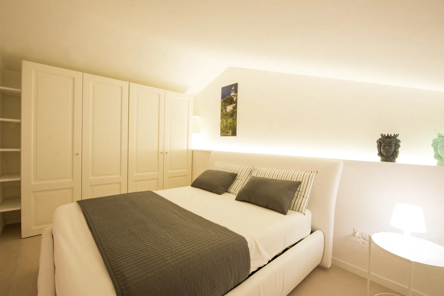 A bright bedroom with a large bed and built-in wardrobes along the wall.