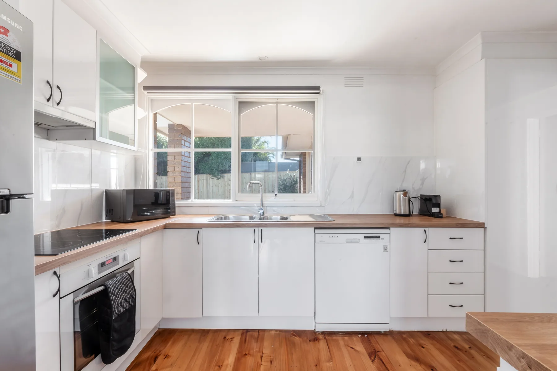 Una cocina luminosa con gabinetes blancos, una encimera y una ventana.
