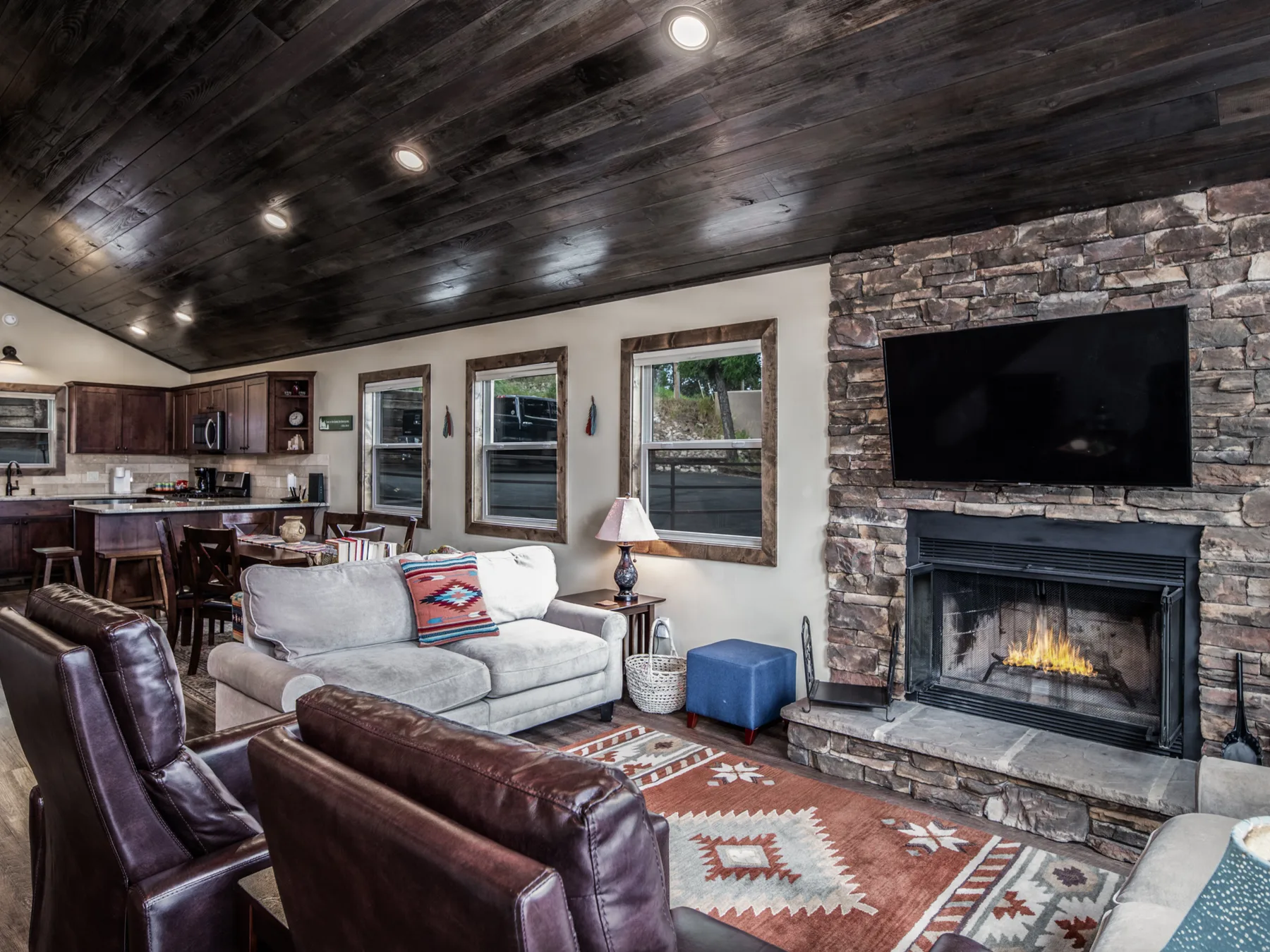A living room with seating, a stone fireplace, and a television.