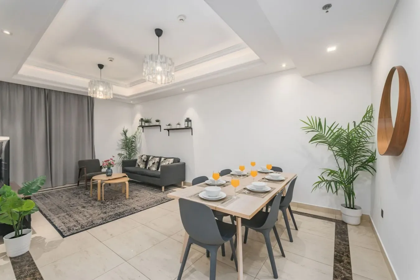 Una luminosa sala de estar y comedor con sofá, mesa de comedor y plantas en macetas.