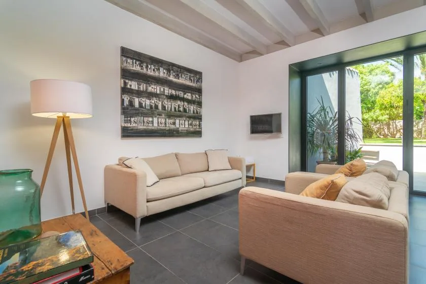Una sala luminosa con dos zonas de asiento y grandes puertas de vidrio frente a la vegetación.
