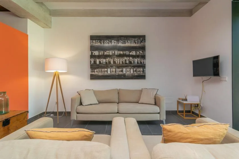 Una sala de estar con asientos, una lámpara de pie y un televisor en la pared.