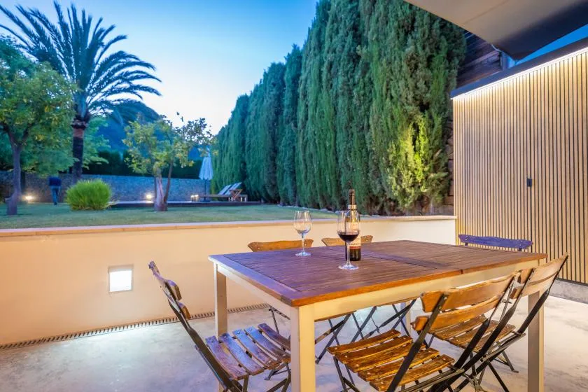 Comedor al aire libre con mesa y sillas junto a un jardín.