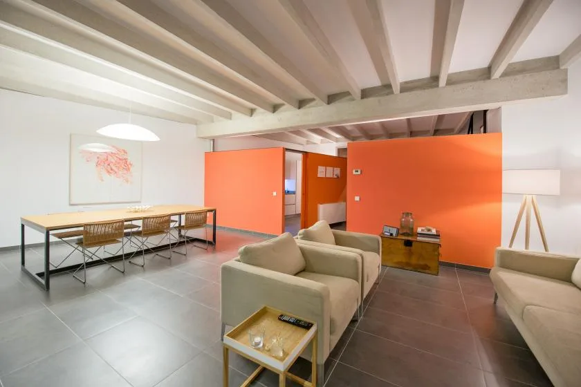 Una sala de estar con asientos y una mesa de comedor bajo vigas expuestas.