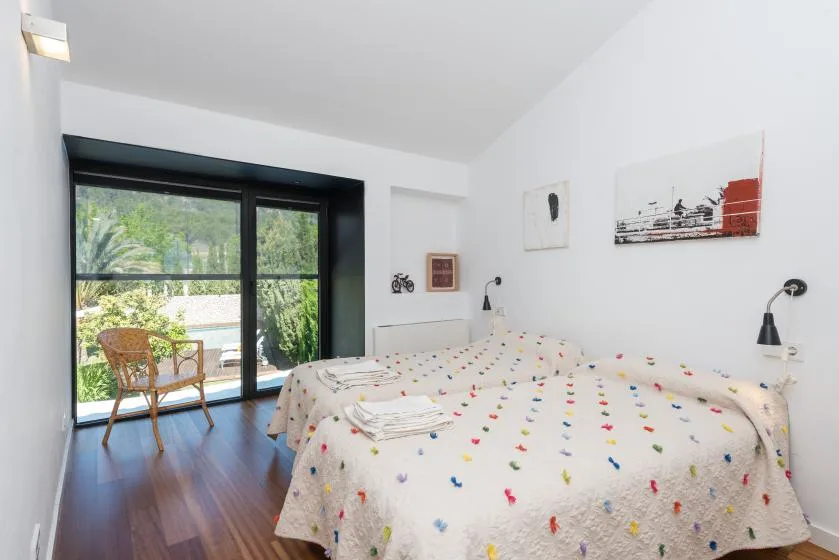 Un dormitorio luminoso con una colcha estampada junto a una gran puerta de vidrio.